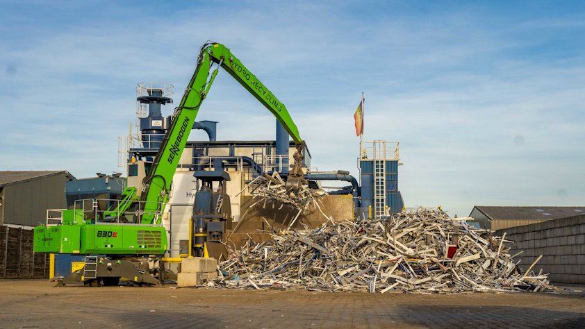 A crane lifting a pile of aluminium scrap