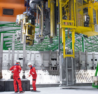 people in red suits standing in front of a large machine